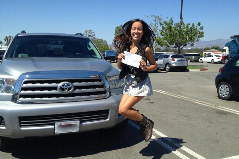 University High School Student Passes Drivers Test Student Jumping in the Air in Celebration in Front of a Truck Parked in a Parking Lot