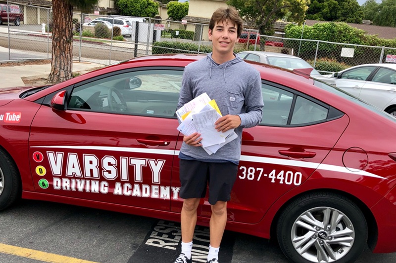 Varsity Driving Academy Receives 2014 Best of Irvine Award Student Standing Next to a Training Vehicle in a Parking Lot