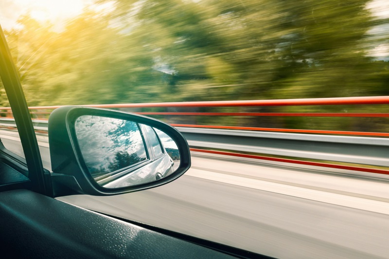 How to Get a Driving License in California View of a Sideview Mirror Driving Down a Highway