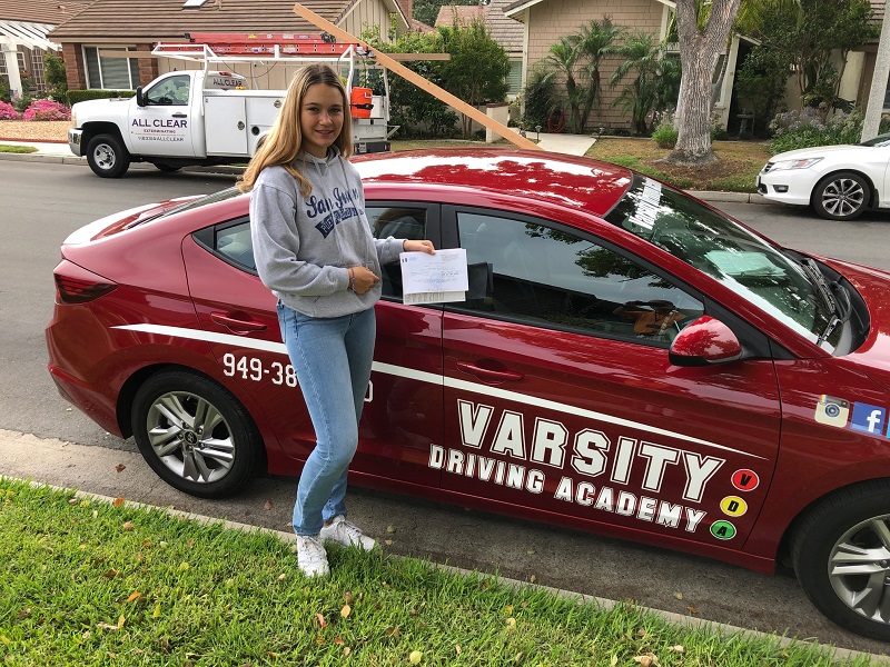 Best Driving Lessons in Lake Forest Female Student Standing Next to Training Vehicle