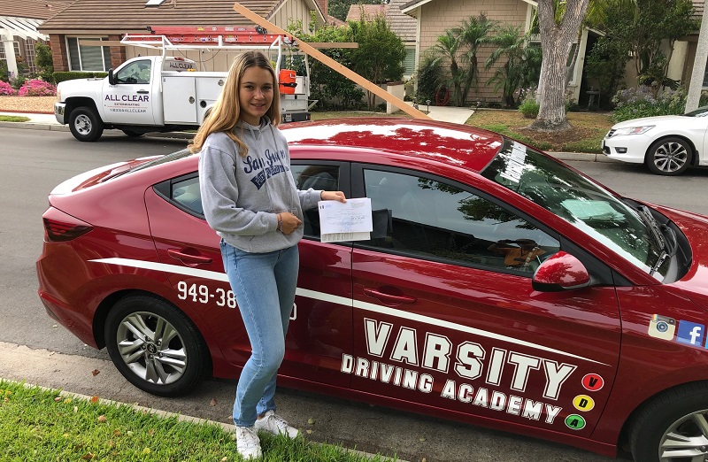Where to Take Driving Lessons in Tustin and Tustin Ranch Female Student Standing Next to a Training Vehicle