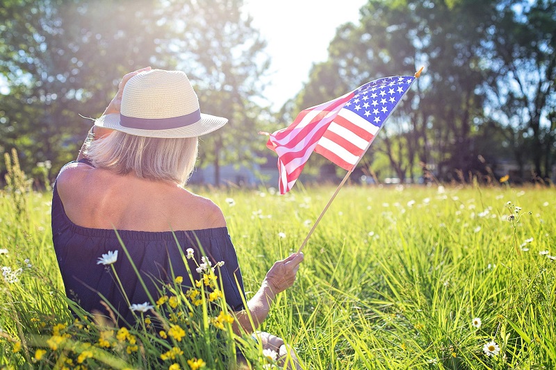 July 4th Things to do in Irvine Woman Sitting in a Field in the Sunlight Holding an American Flag