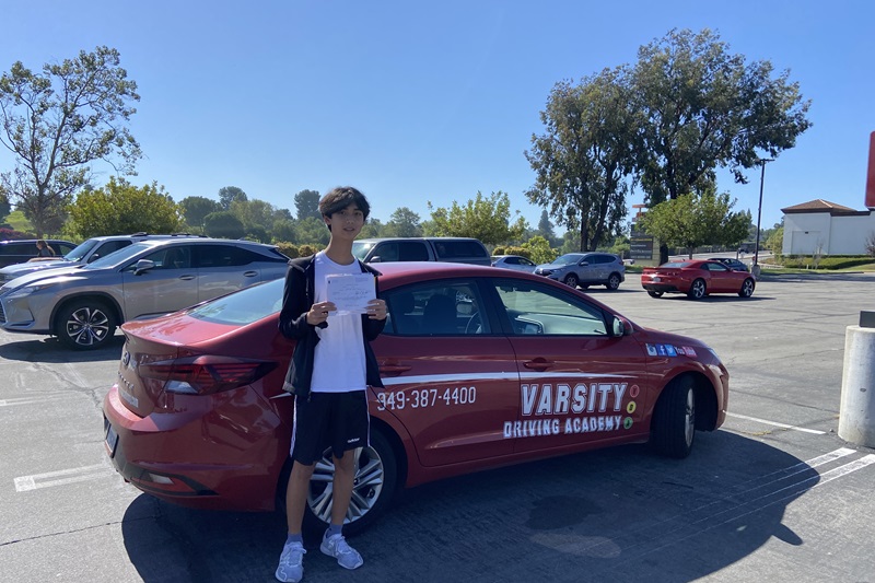 Which Driving School for Woodbridge High School Irvine a Student Standing Next to a Training Vehicle in a Parking Lot