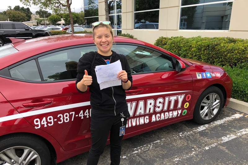 Best Behind the Wheel Training Near Me Irvine Student Standing Next to a Training Vehicle in a DMV Parking Lot