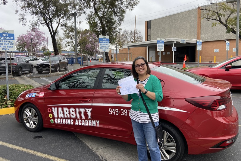 Best Driving School Near Me Newport Beach Student Standing Next to a Training Vehicle Parked in a DMV Parking Lot