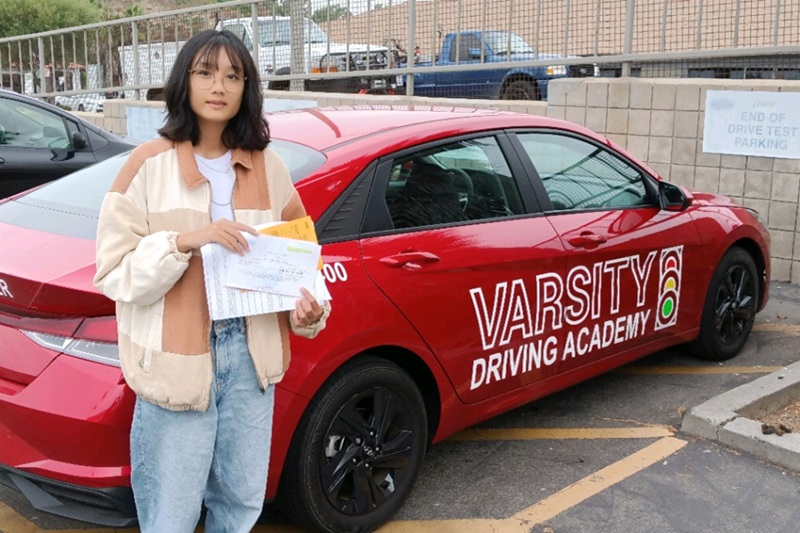 Best Driving School Near Me Newport Beach Student Standing Next to a Training Vehicle in a Parking Lot Near a DMV