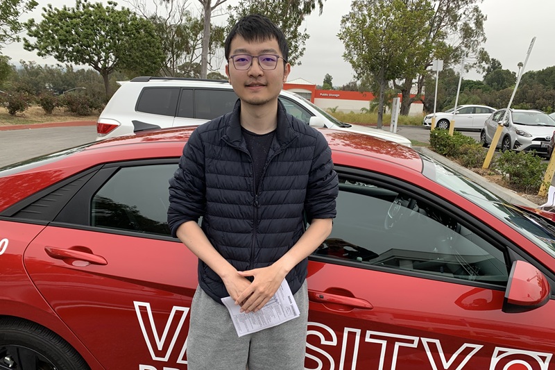 Best Adult Driving School in Newport Beach a Student Standing Next to a Training Vehicle in a Parking Lot