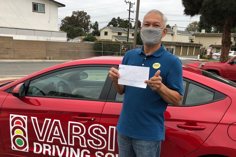 Best Adult Driving School in Tustin an Adult Student Standing Next to a Training Vehicle in a DMV Parking Lot