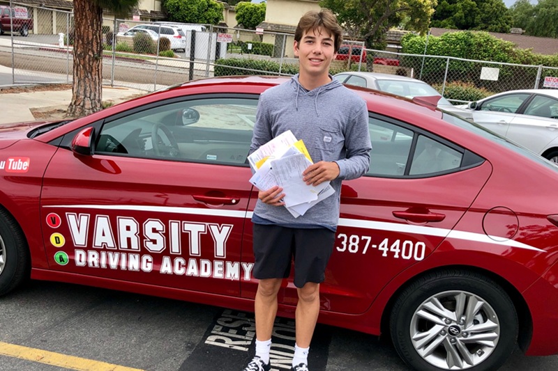 Orange Coast College Driving School Student Standing Next to a Training Vehicle in a Parking Lot